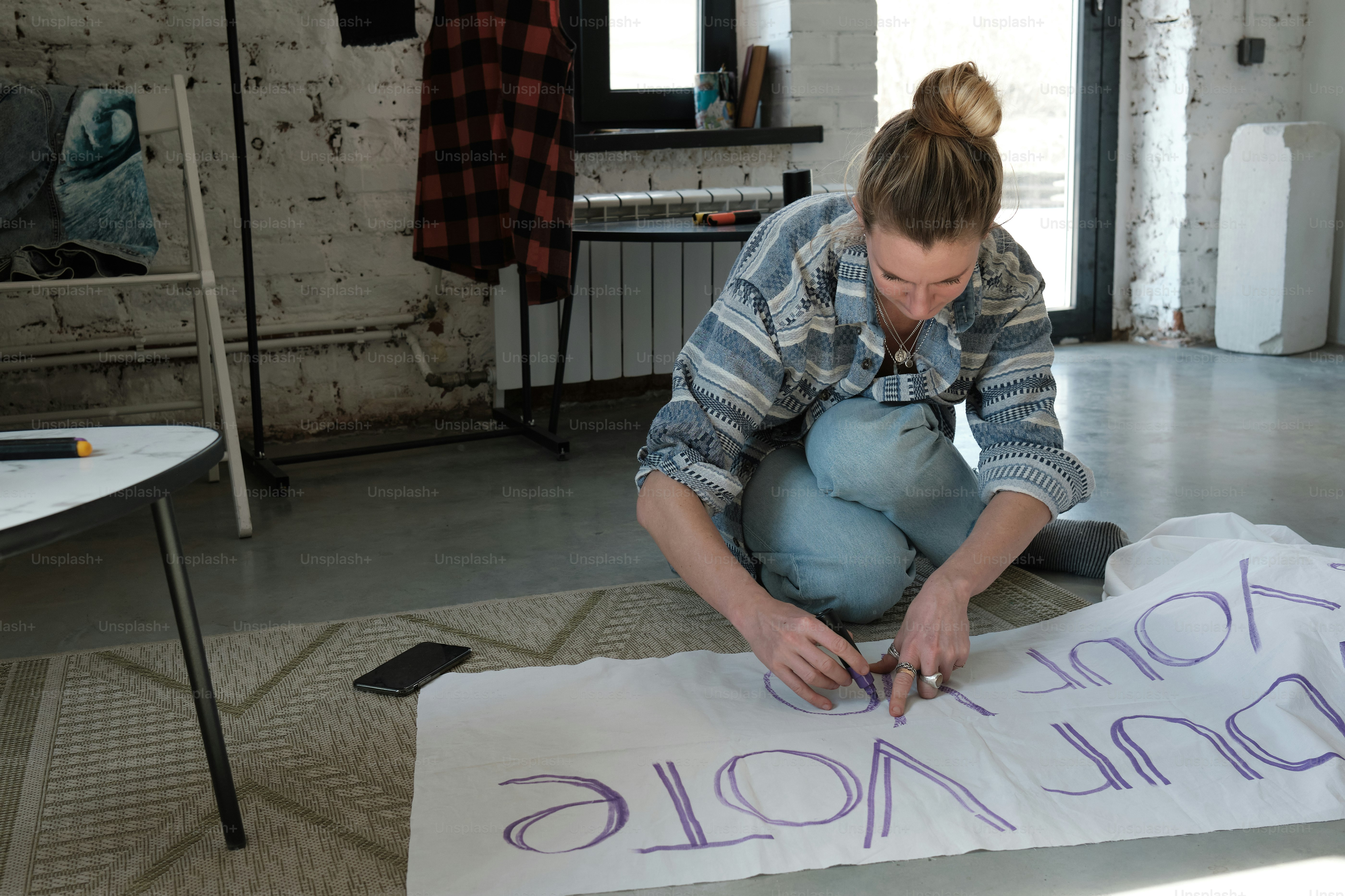 a woman sitting on the floor writing on a piece of paper