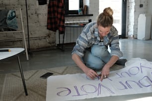 a woman sitting on the floor writing on a piece of paper