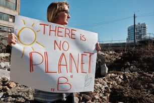 a woman holding a sign that says there is no planet b