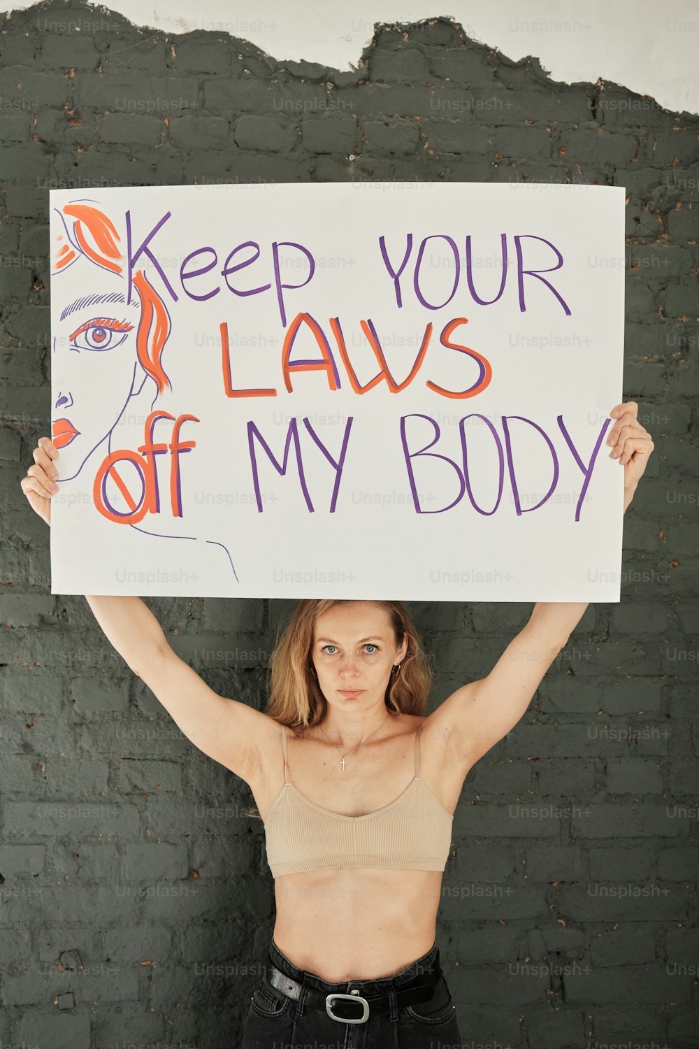 a woman holding a sign that says keep your laws off my body