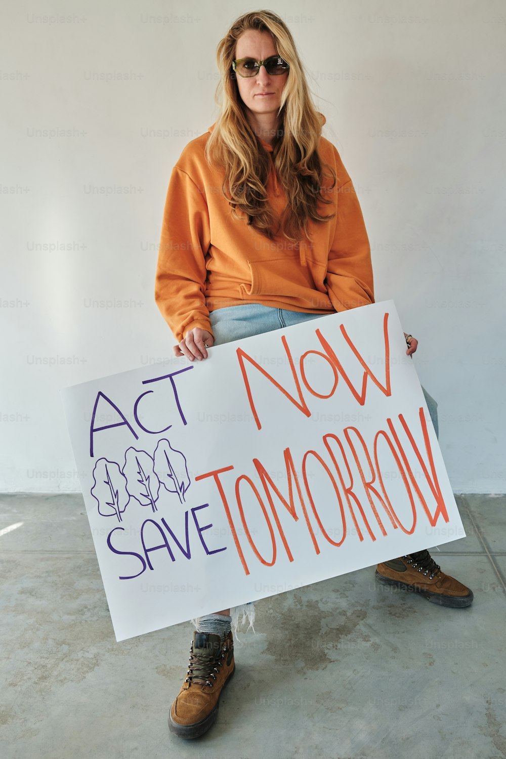 Una mujer sosteniendo un cartel que dice Actúa ahora, salva mañana