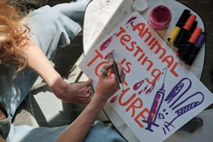 Una mujer está escribiendo en un letrero con crayones