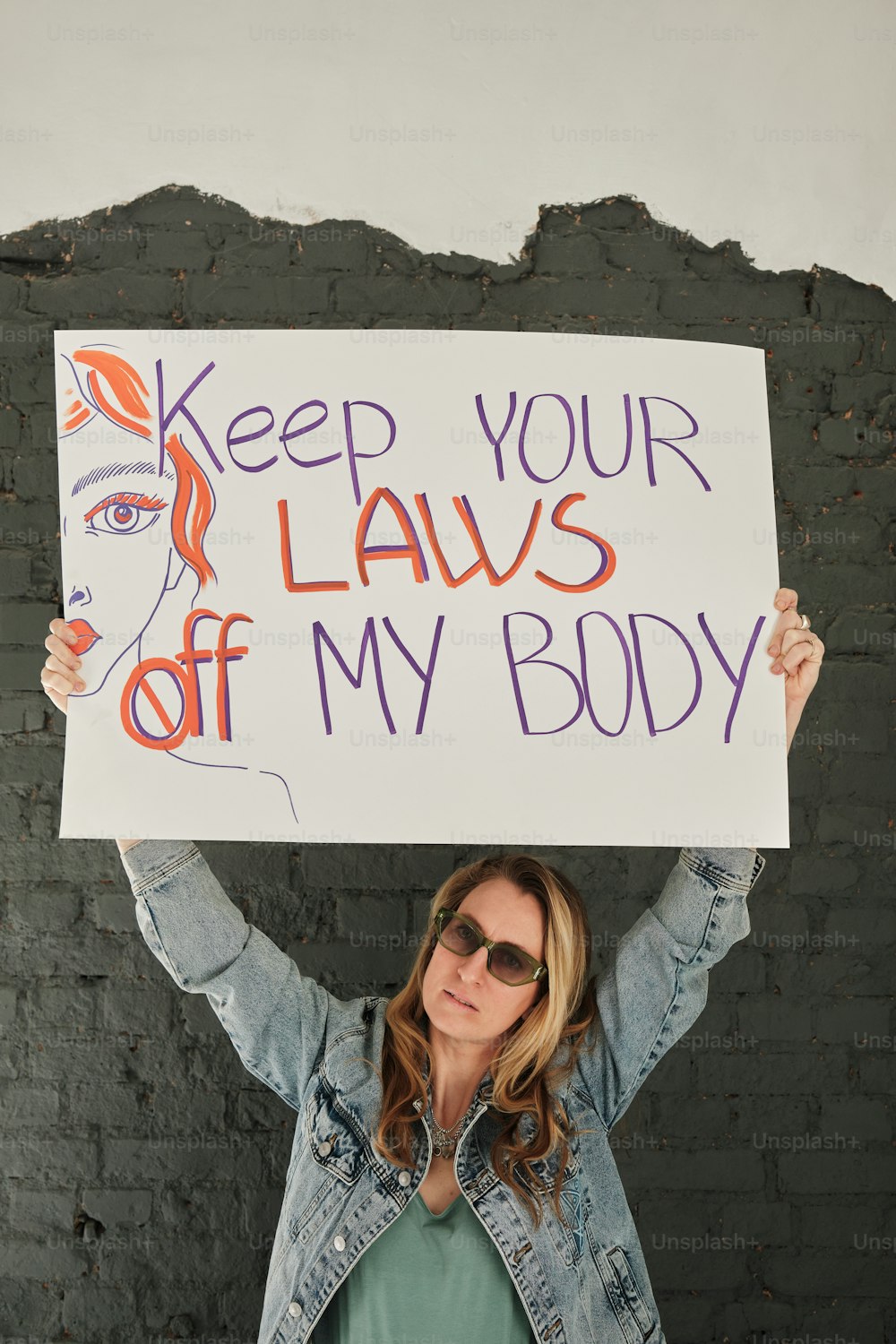 a woman holding a sign that says keep your laws off my body