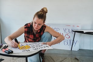 a woman sitting at a table writing on a piece of paper