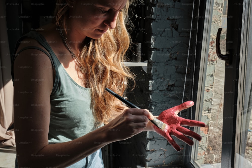 a woman holding a paintbrush and a pair of red gloves