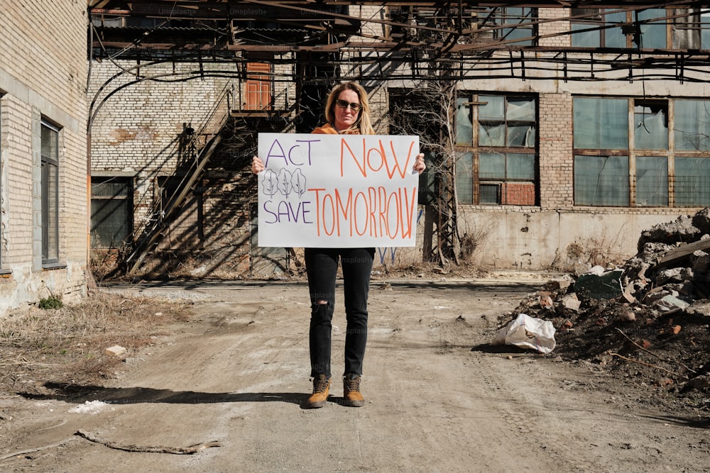 a woman holding a sign that says act now save tomorrow