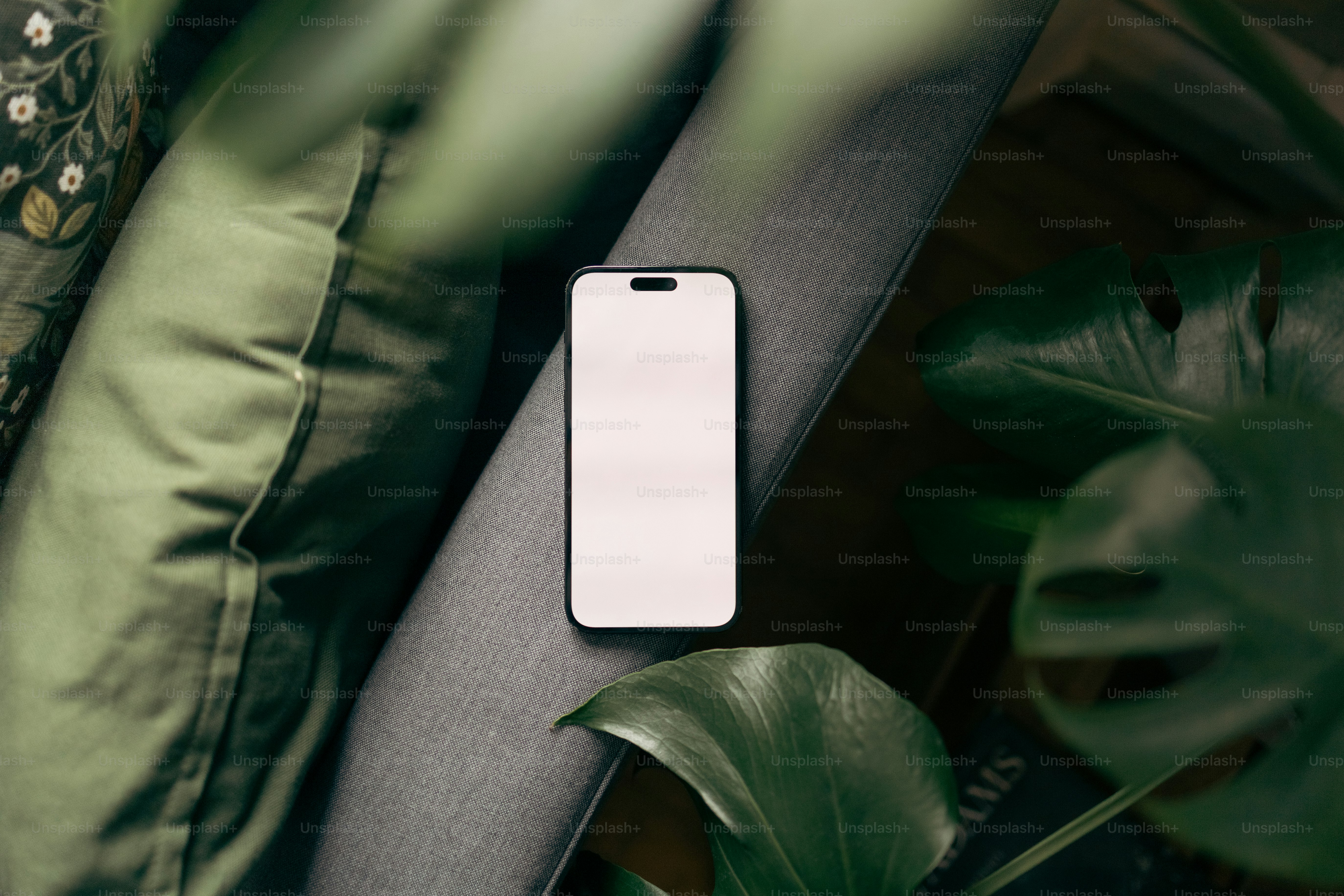 un teléfono celular sentado encima de una mesa al lado de una planta