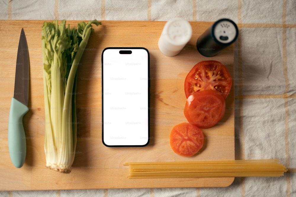a cutting board topped with a cell phone and vegetables