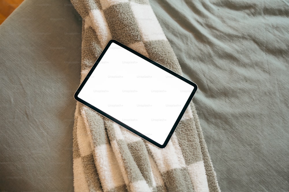 um computador tablet sentado em cima de uma cama