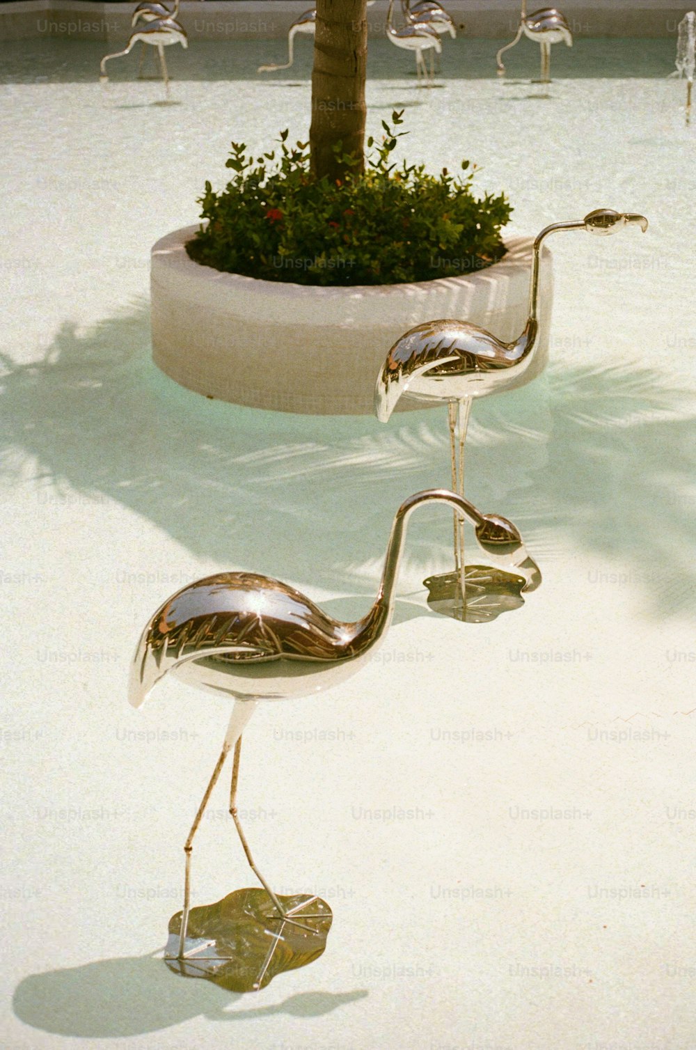 a couple of metal birds standing next to a tree