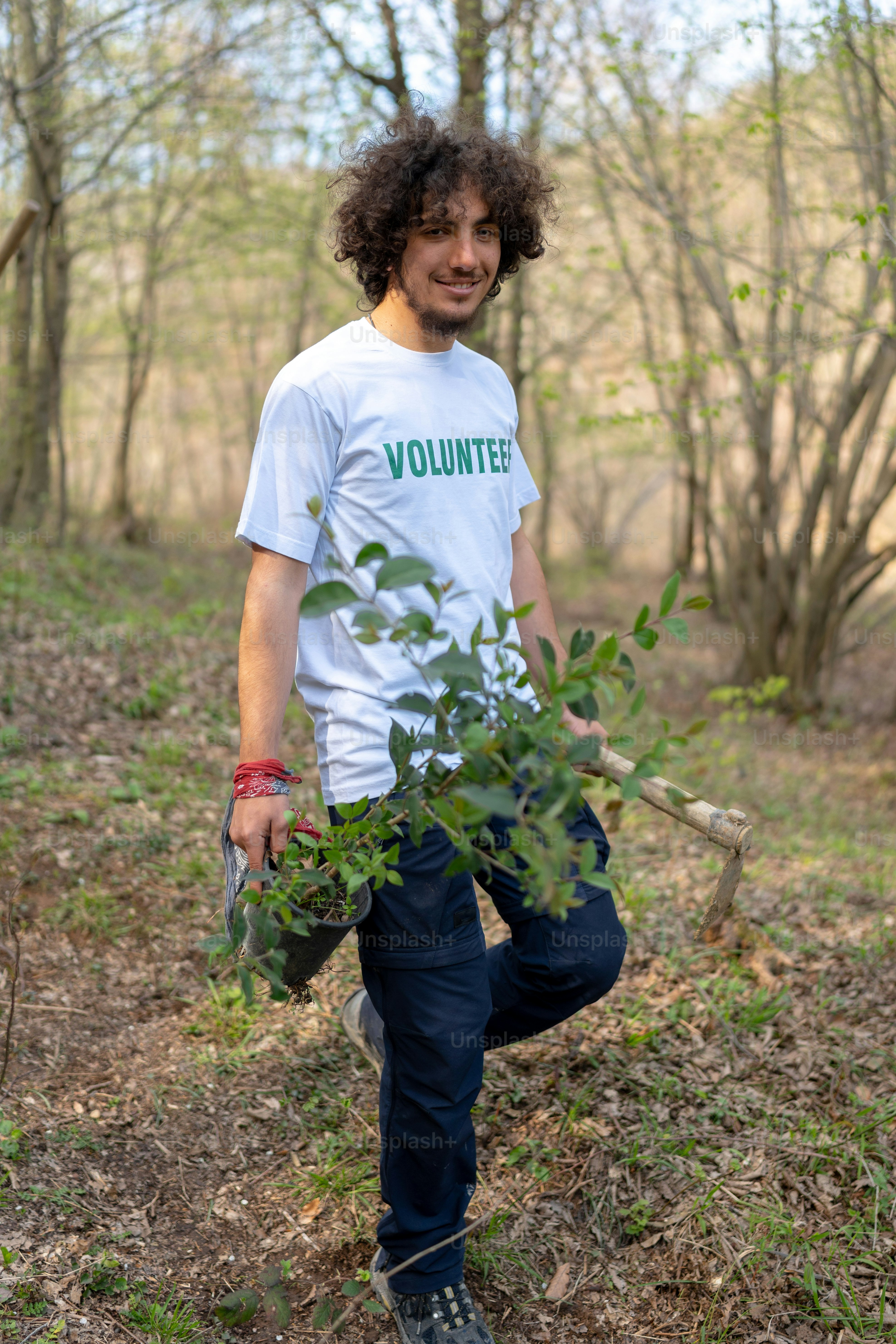 a man standing in the woods holding a tree branch
