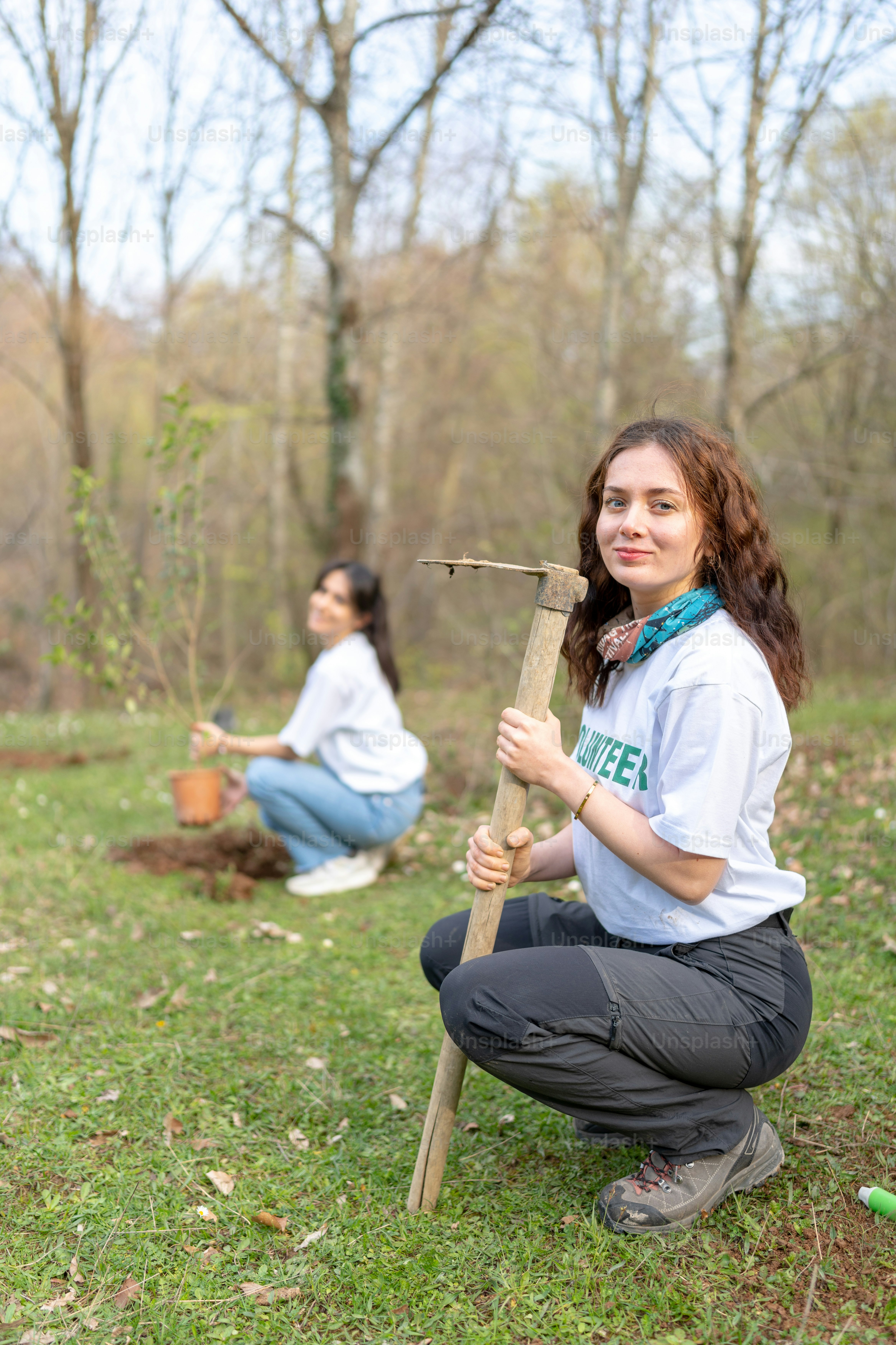 Une femme agenouillée à côté d’un arbre