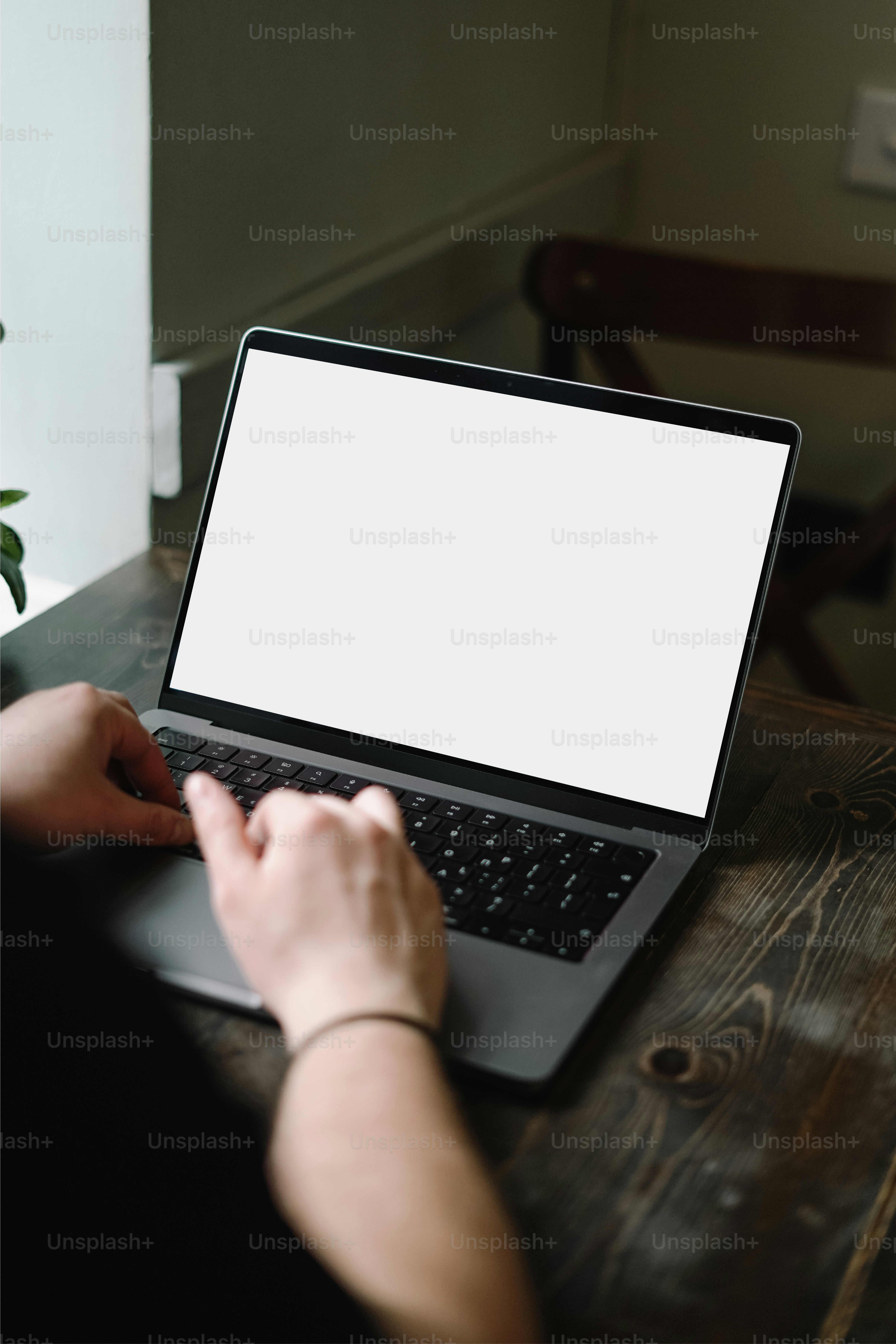 Una persona escribiendo en una computadora portátil en una mesa de madera