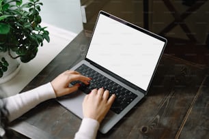 una persona escribiendo en una computadora portátil sobre una mesa de madera