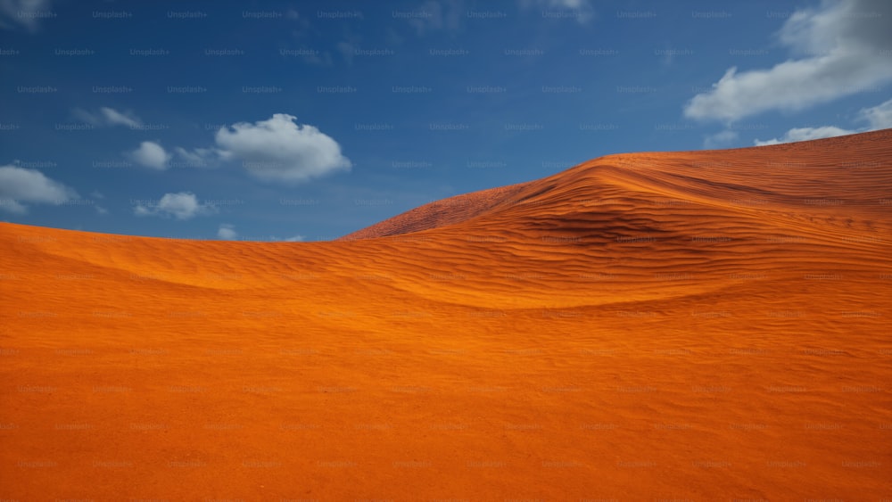 Una duna de arena naranja con un cielo azul en el fondo