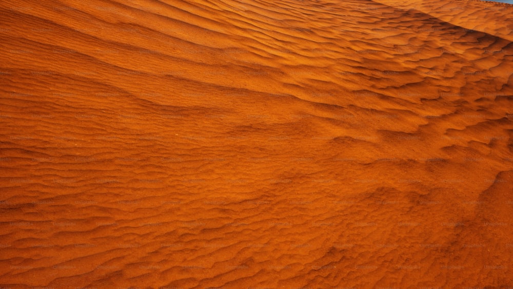 an orange desert with a blue sky in the background