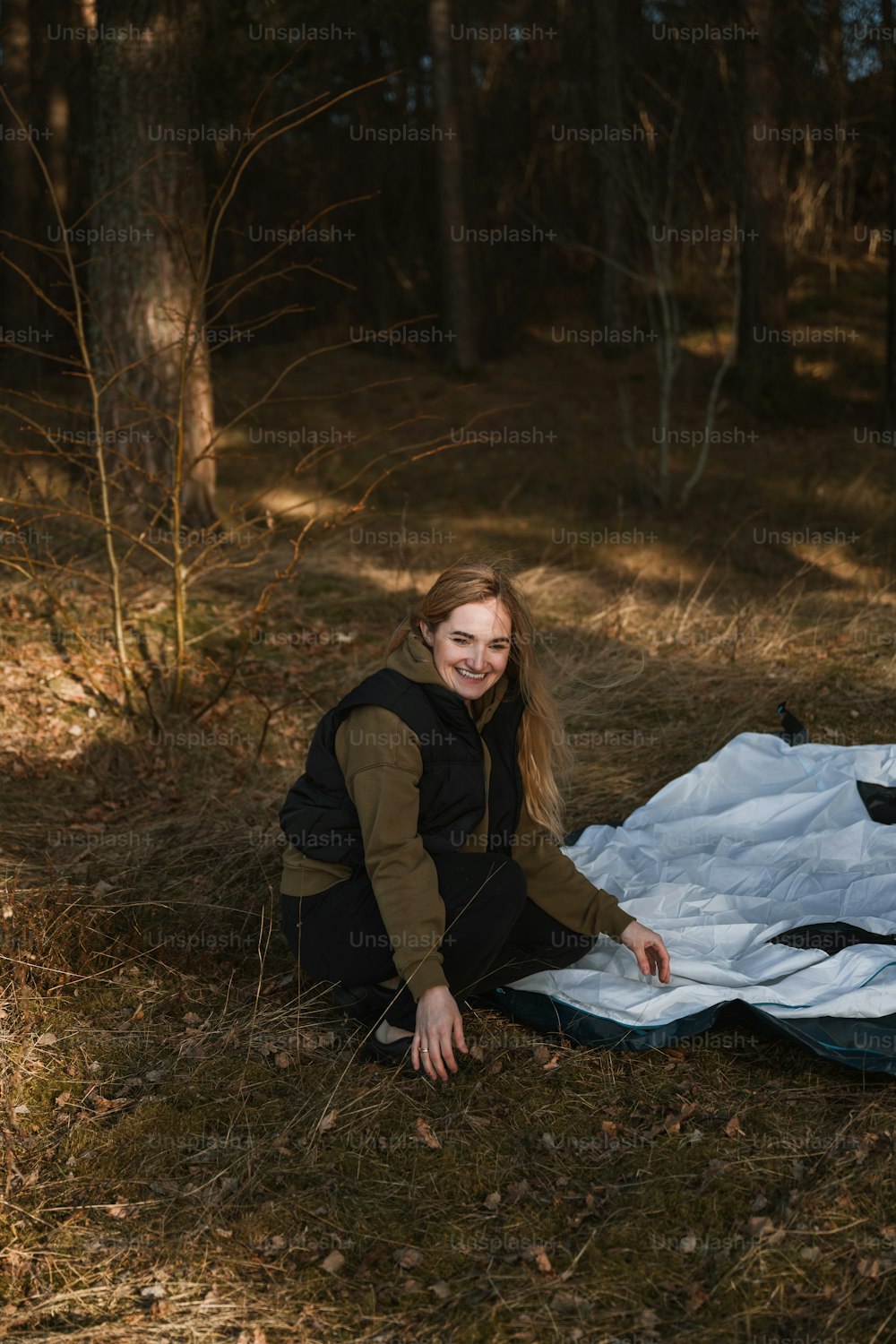 a woman sitting on a blanket in the woods