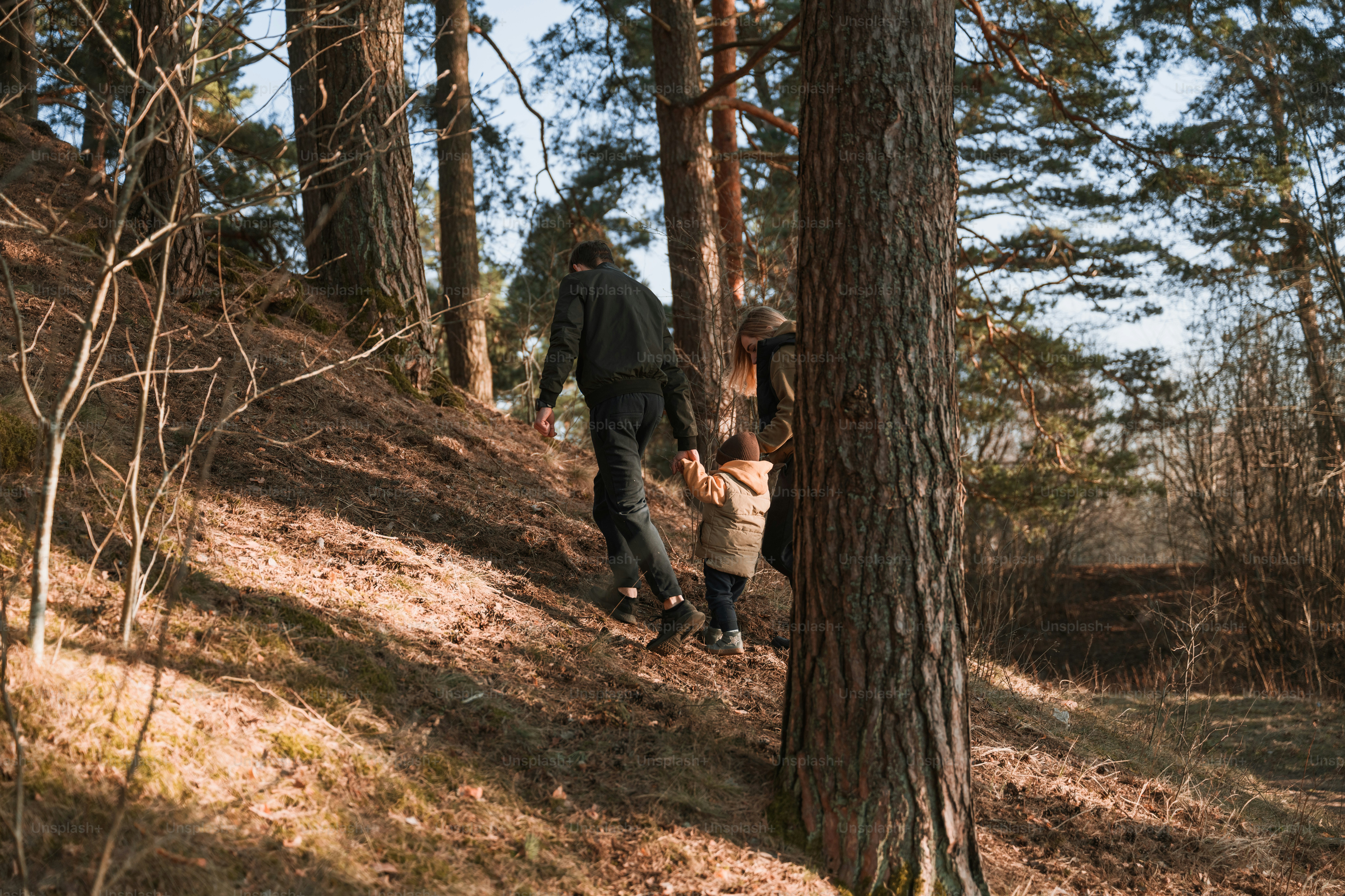 a man and a child walking up a hill in the woods