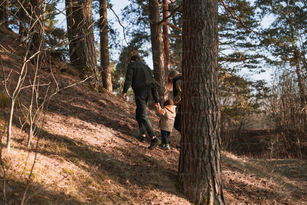 a man and a child walking up a hill in the woods