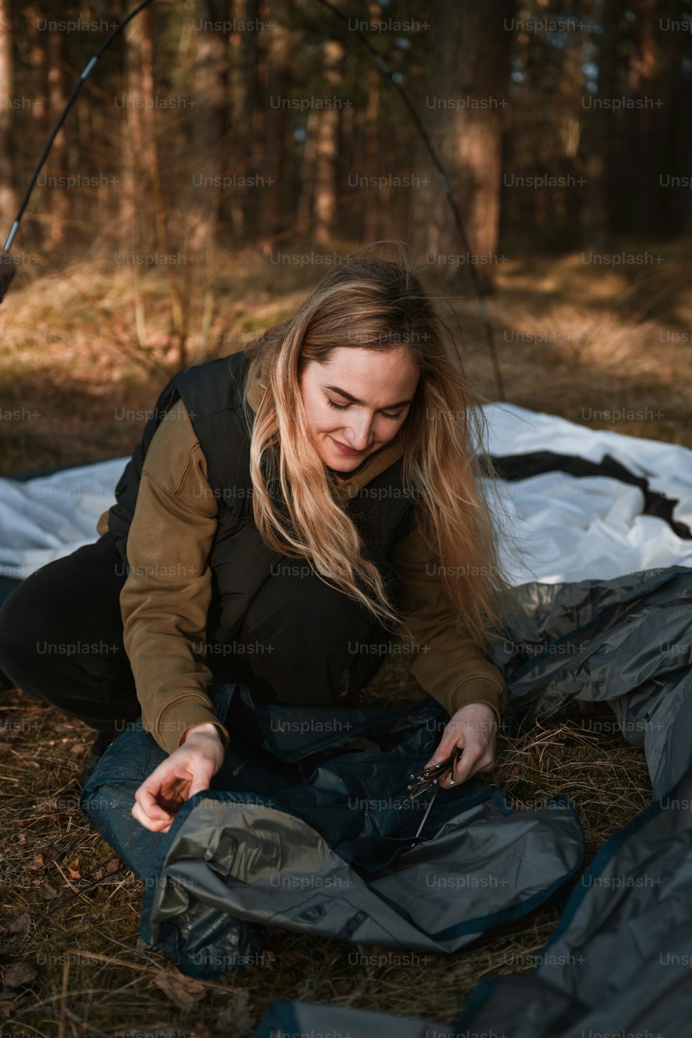 a woman sitting on a tarp in the woods