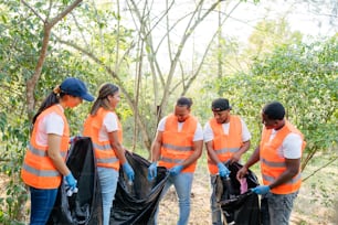 a group of people wearing orange vests and holding trash bags