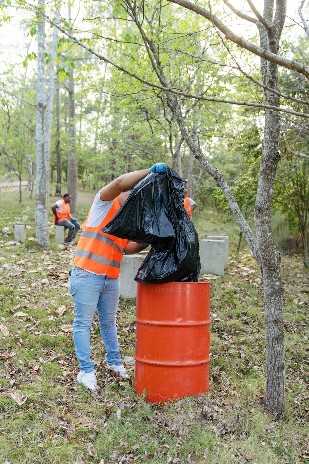 a man in an orange vest is picking up a trash can
