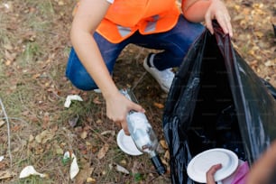 a woman in an orange vest is picking up trash