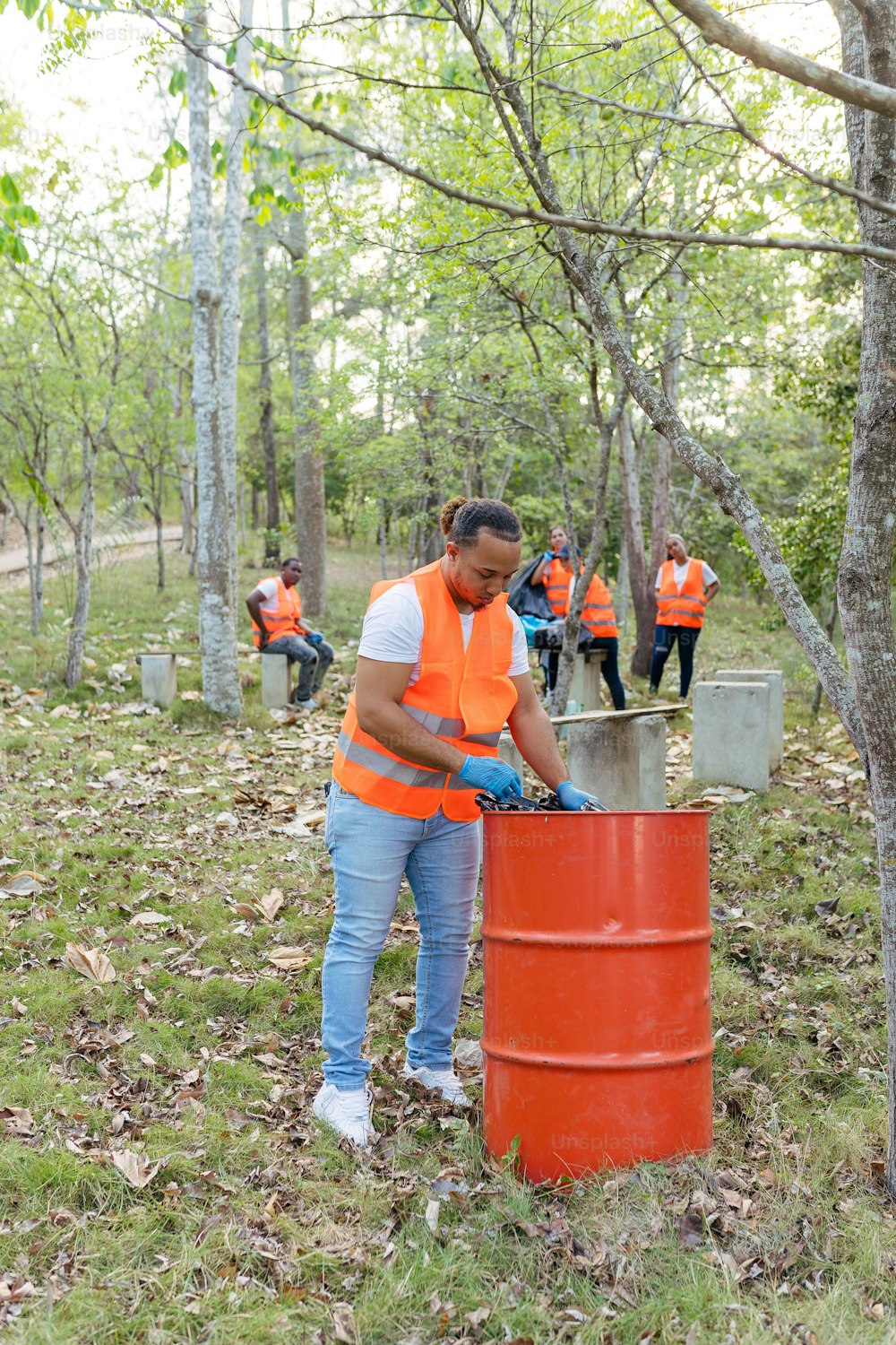 a group of people in orange vests standing around a barrel