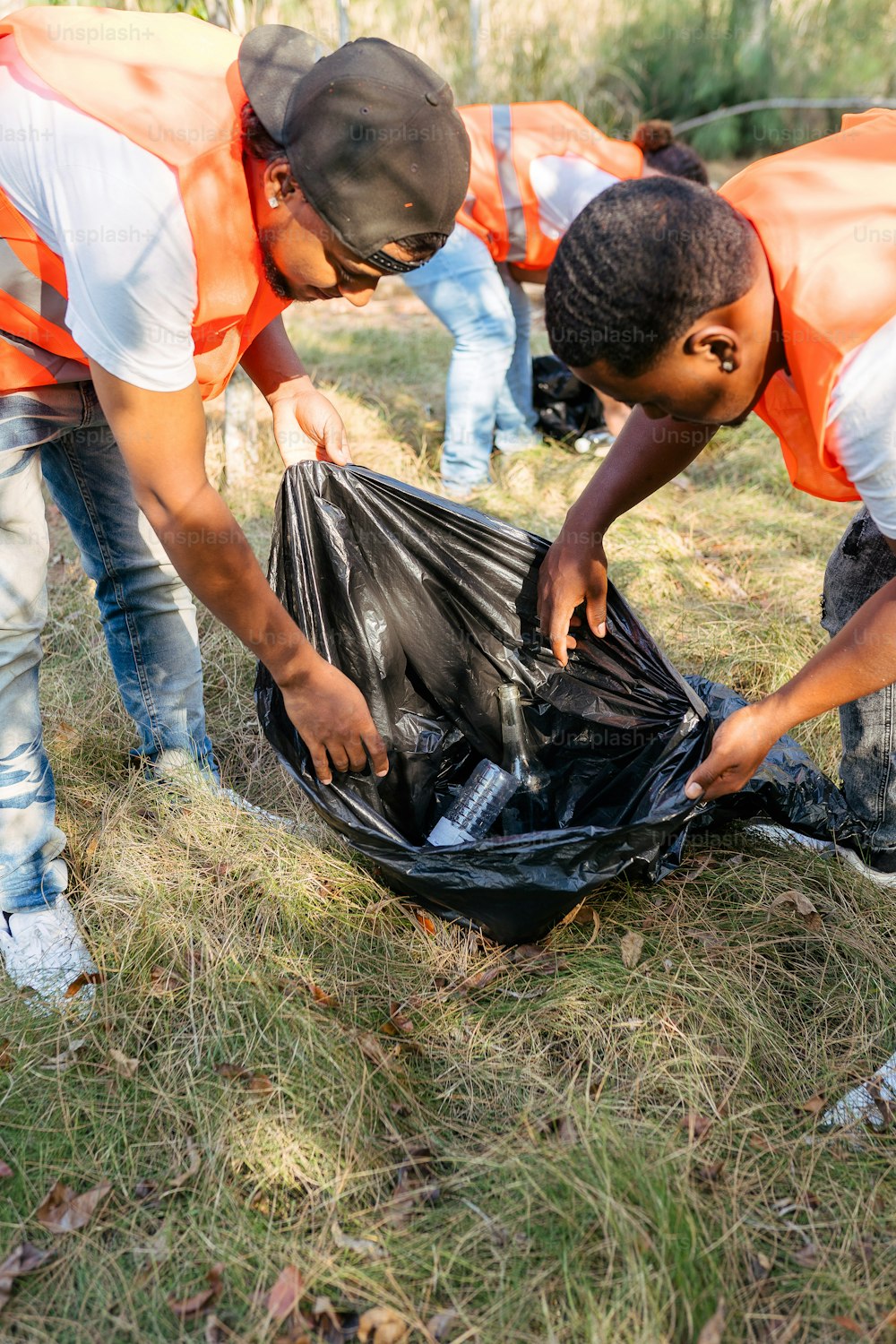 a group of men in orange vests picking up trash