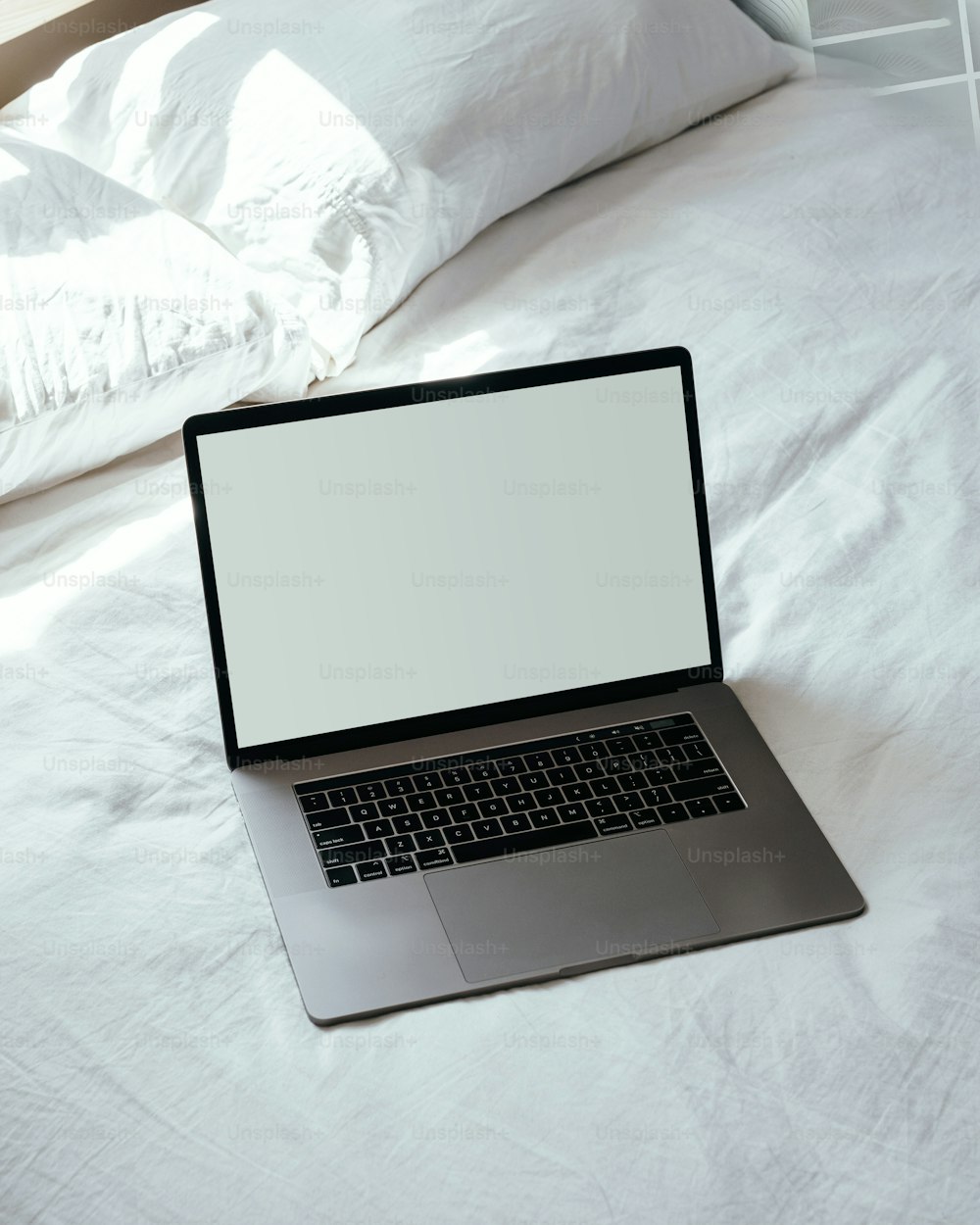 Ein Laptop, der auf einem weißen Bett sitzt