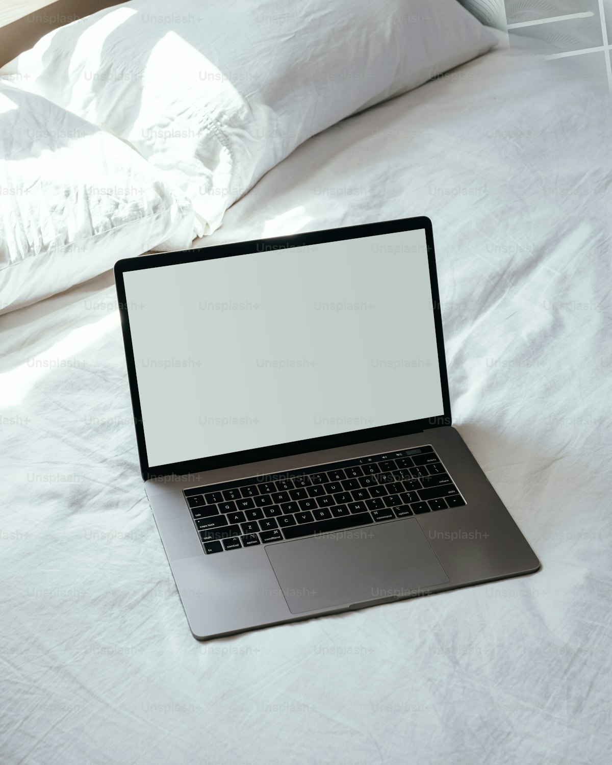A laptop computer sitting on top of a white bed