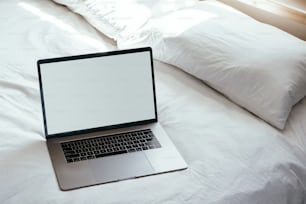 um computador portátil sentado em cima de uma cama branca