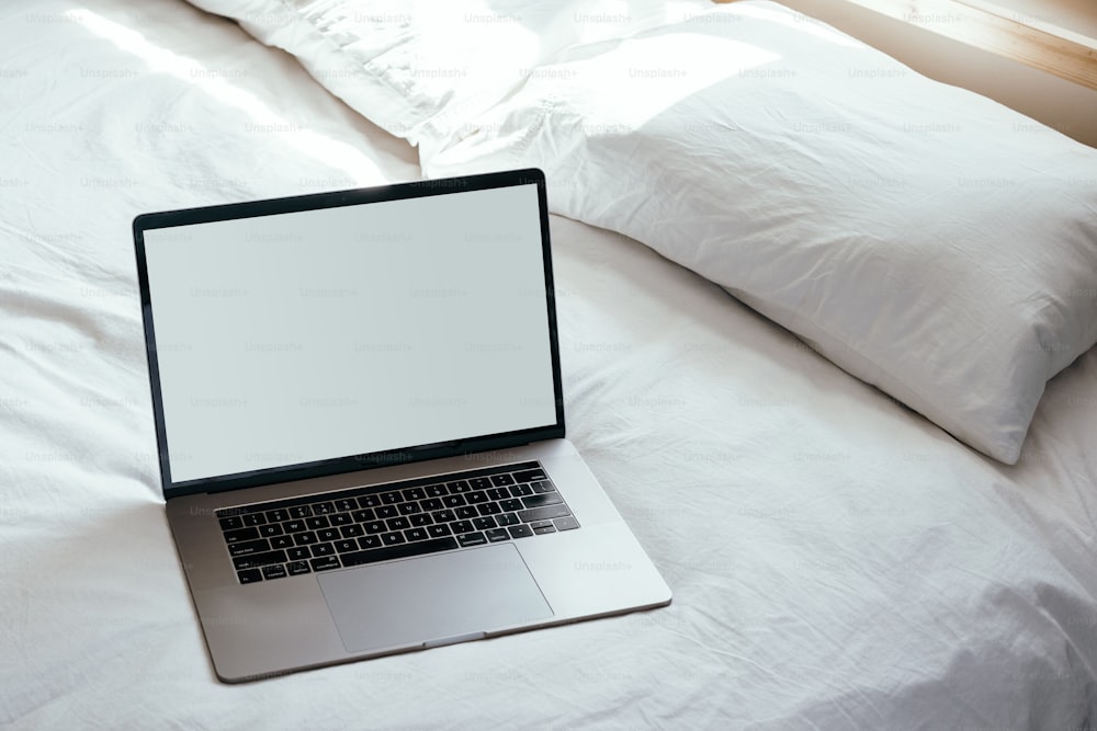 a laptop computer sitting on top of a white bed