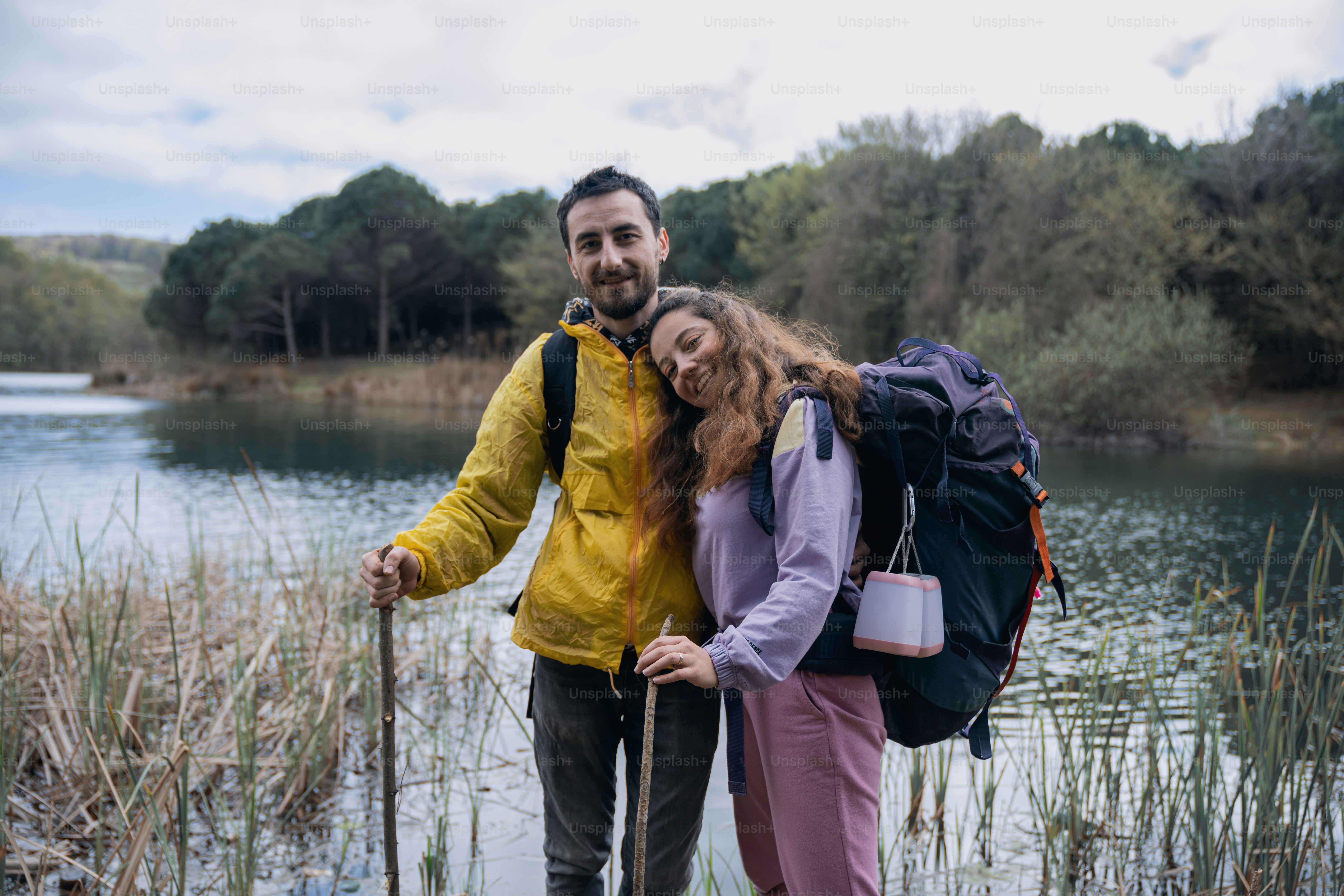 A man and a woman standing next to each other in front of a lake photo ...