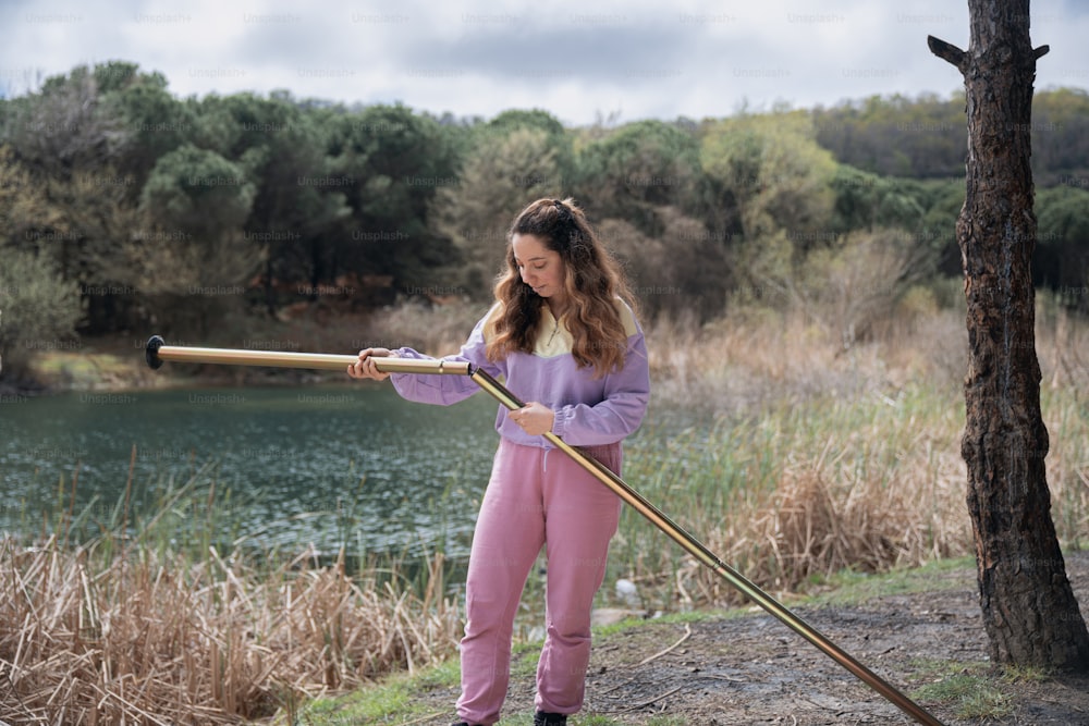 a young girl holding a stick near a body of water