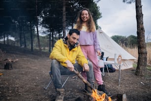 a man and a woman standing next to a campfire