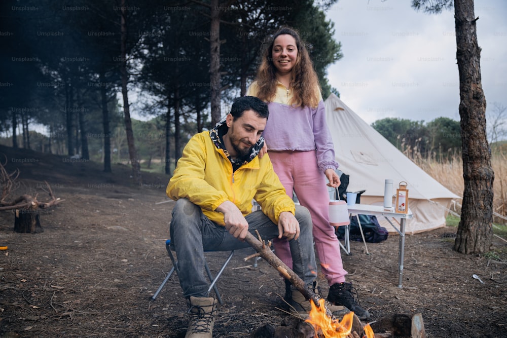 a man and a woman standing next to a campfire