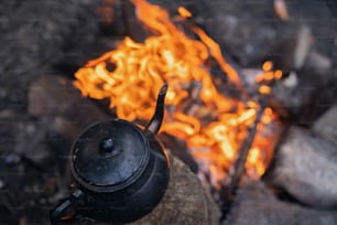 a kettle sitting on top of a rock next to a fire