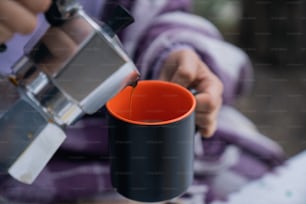 eine Person, die eine Tasse Kaffee aus einer Kaffeemaschine einschenkt