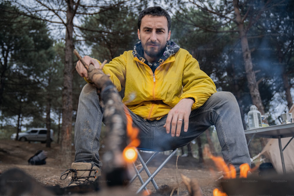 a man sitting in a chair next to a campfire