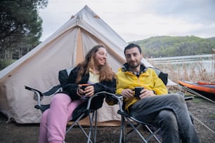 a man and a woman sitting in chairs in front of a tent