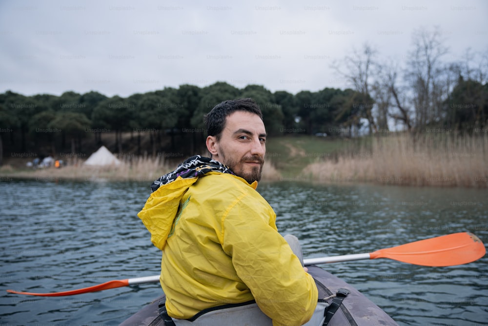 a man in a yellow jacket paddling a kayak