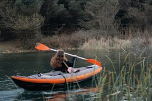 a woman in an orange and black kayak paddling down a river