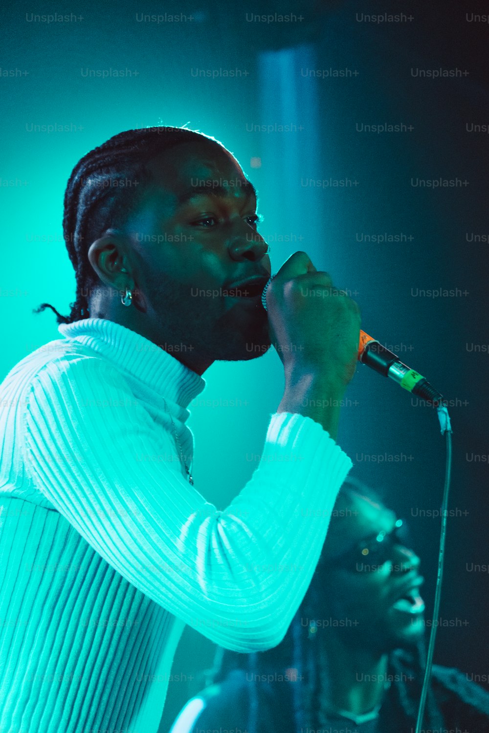 a man with dreadlocks singing into a microphone