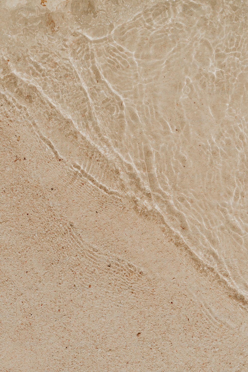 une plage de sable avec une vague arrivant sur le rivage