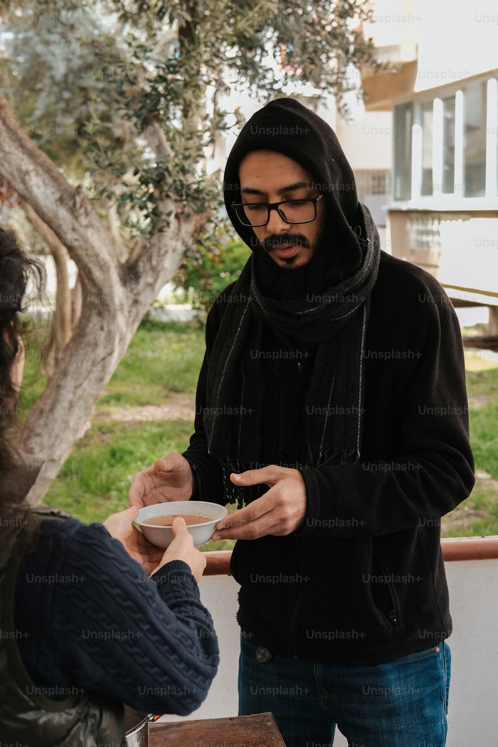 a man in a hoodie is handing a plate to a woman