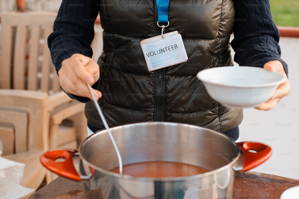 a woman in a vest is stirring a bowl of soup