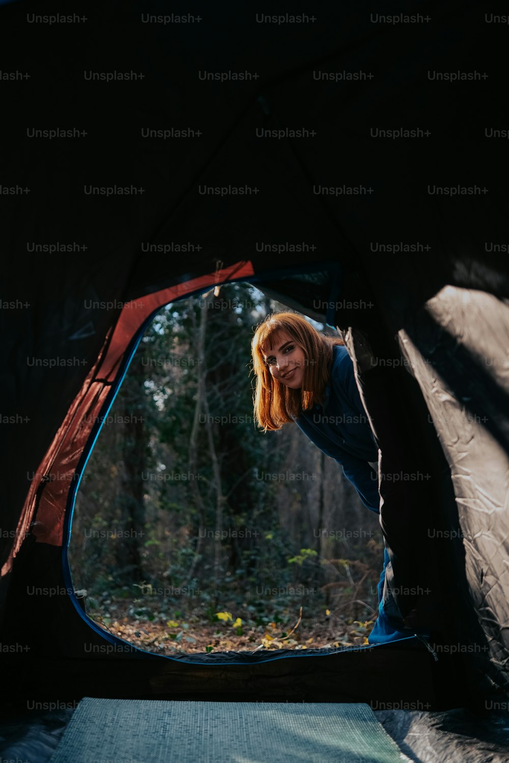 a woman standing inside of a tent in the woods