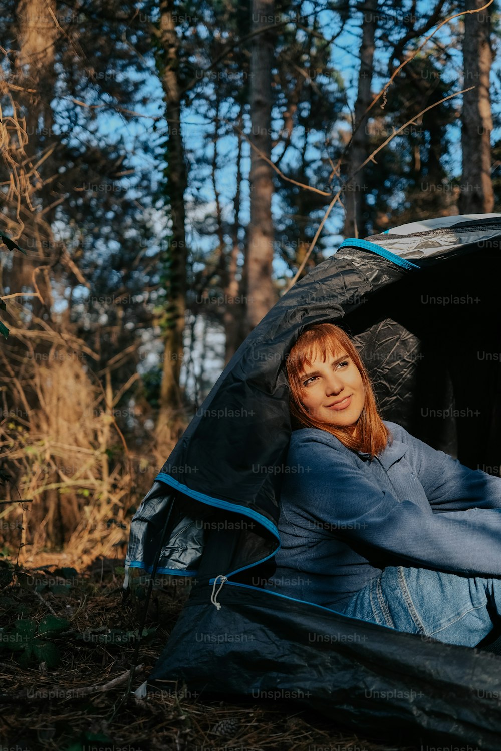 a woman sitting inside of a tent in the woods