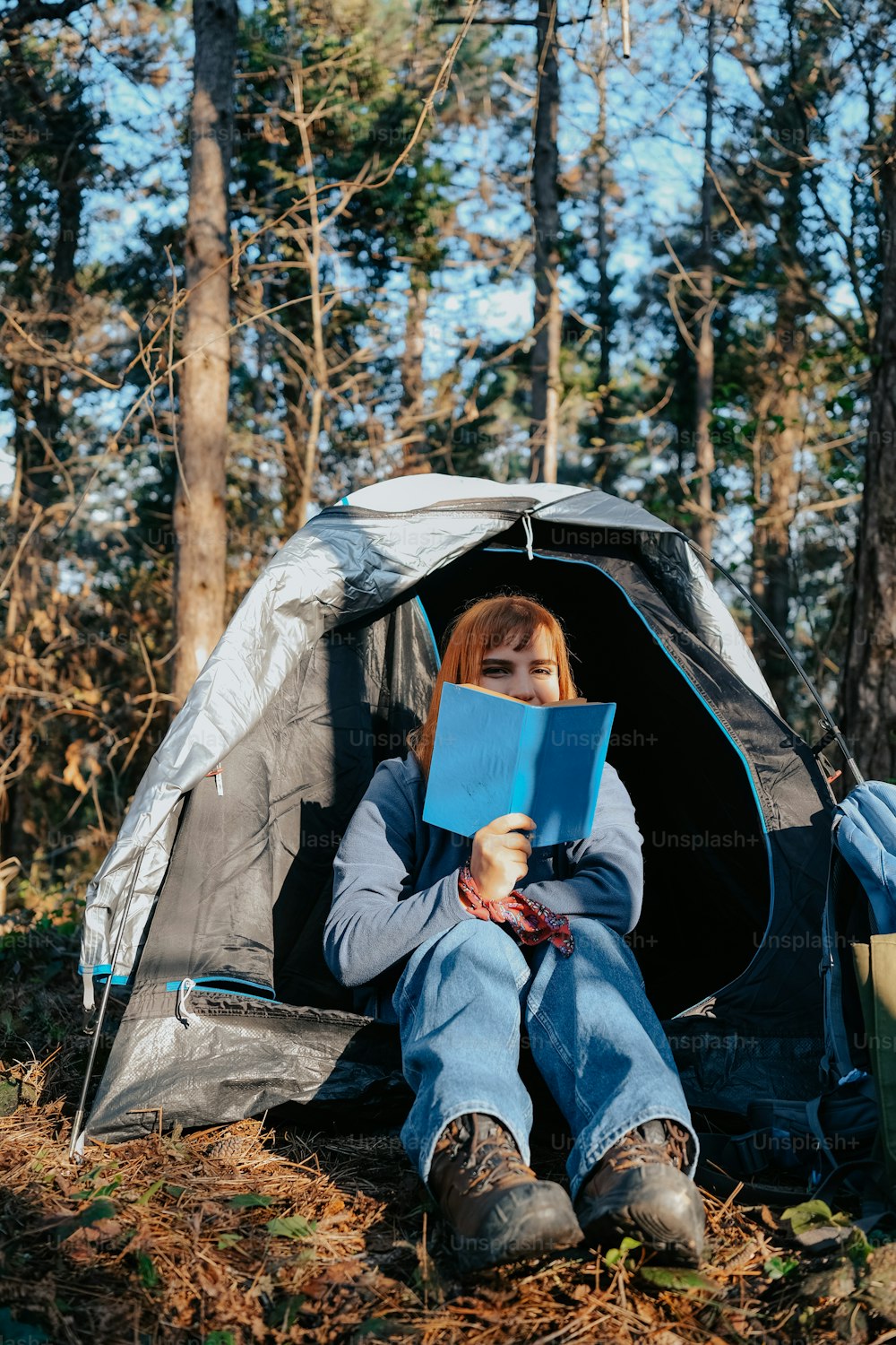 a woman sitting in a tent reading a book